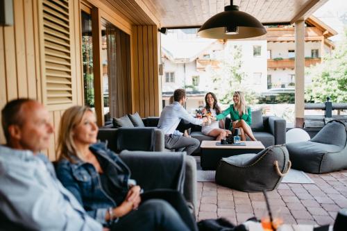 a group of people sitting on couches in a patio at ALMHOF Alpin Apartments & Spa in Dienten am Hochkönig