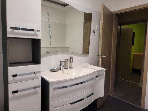 La salle de bains blanche est pourvue d'un lavabo et d'un miroir. dans l'établissement LI-DO Vendégház, à Balatonfüred