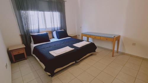 een kleine slaapkamer met een bed en een bureau bij STAY Nissi Class Apartment in Ayia Napa