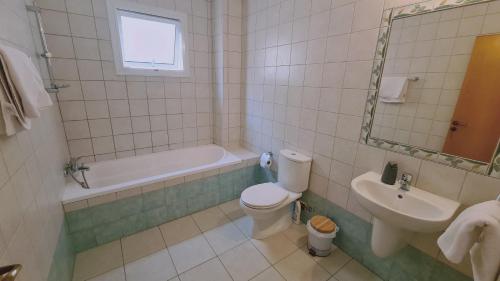 een badkamer met een toilet, een bad en een wastafel bij STAY Nissi Class Apartment in Ayia Napa
