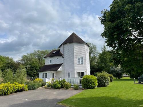 a large white house with a gambrel roof at Windrush Turret Lodge in South Cerney