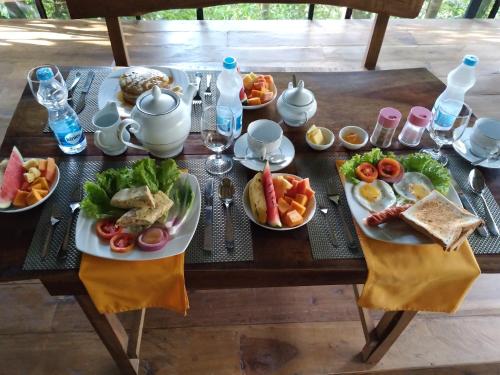 a table with plates of food on top at Sinharaja Kurulu Ella Eco Resort in Deniyaya