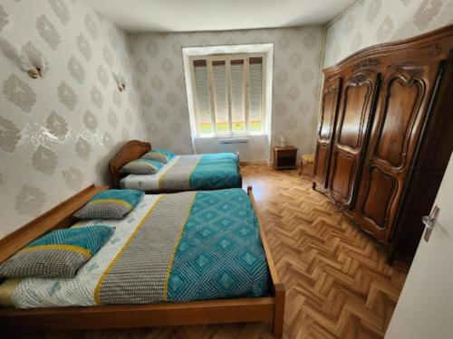 1 dormitorio con 2 camas y armario de madera en Gîte43, en Decazeville