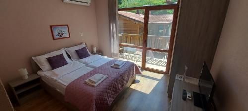 ein Schlafzimmer mit einem Bett und einem großen Fenster in der Unterkunft Mini Complex Rilski Terasi in Saparewa Banja