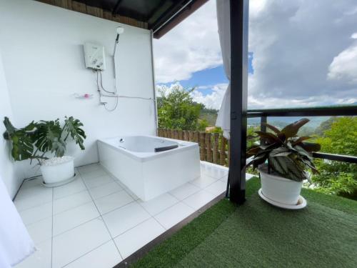a white bathroom with a tub and plants on a balcony at Phu Fahsai Homestay in Mon Jam