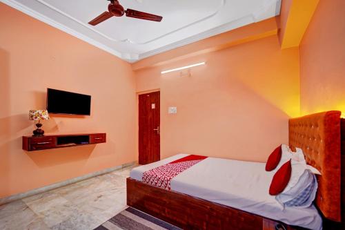 1 dormitorio con 1 cama y TV de pantalla plana en OYO Flagship Wellfood Inn, en Patna