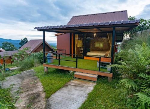 a small house with a large window in the grass at Phu Fahsai Homestay in Mon Jam