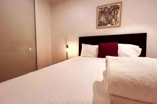 a bedroom with a large white bed with a red pillow at Nest Apartments on Rose Lane in Melbourne