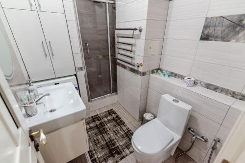 een badkamer met een toilet, een wastafel en een douche bij ЖК Вавилон in Alma-Ata