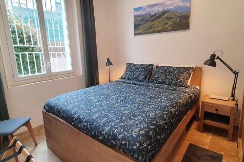 une chambre avec un lit avec des draps bleus et une fenêtre dans l'établissement Two bedroom apartment garden parking near beaches, à La Ciotat