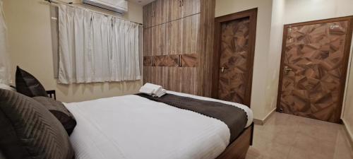 ein Schlafzimmer mit einem weißen Bett und einer Holztür in der Unterkunft The Candy Studio in Ranchi