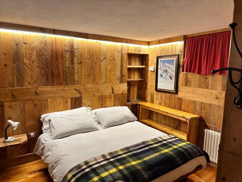 a bedroom with a bed and a wooden wall at Baita Meyen - Val Ferret in Courmayeur