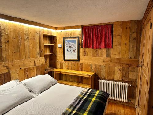 - une chambre avec des murs en bois, un lit et une fenêtre dans l'établissement Chalet Meyen - Val Ferret, à Courmayeur
