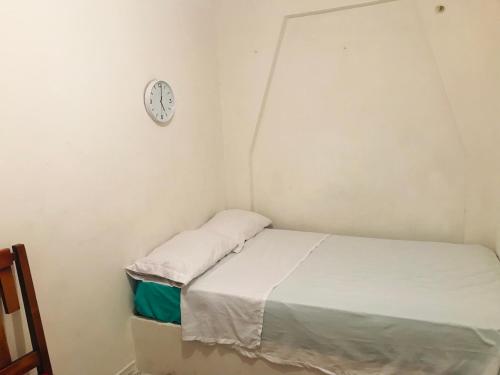 a small bed in a room with a clock on the wall at hostal la 18 in Pereira