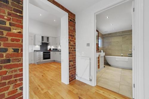 a bathroom with a brick wall and a bath tub at The Stables Rectory Farm in Halstead