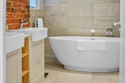 a bathroom with a large tub and two sinks at The Stables Rectory Farm in Halstead