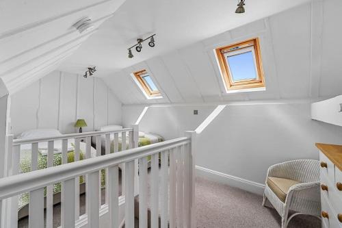 a white attic room with a staircase and a crib at The Stables Rectory Farm in Halstead