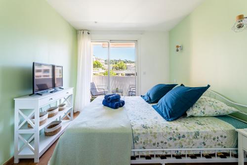 ein Schlafzimmer mit einem Bett mit blauen Kissen und einem TV in der Unterkunft Cassis - Le Capucine, 4pers, terrasse, classé 3 étoiles in Cassis