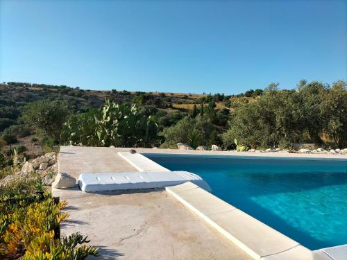 uma piscina azul com uma chaise longue ao lado em Casa Giufà B&B em Chiaramonte Gulfi