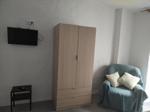 sala de estar con silla azul y armario en Apartamentos La Campana 1, en Jerez de la Frontera