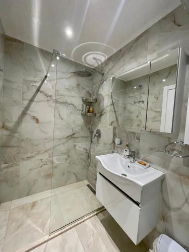 uma casa de banho branca com um lavatório e um chuveiro em Elma's Apartament Center of Tirana em Tirana