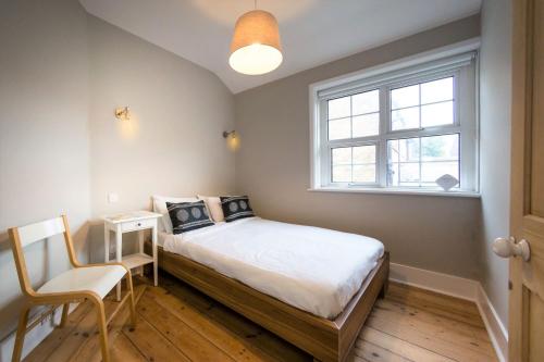 ein Schlafzimmer mit einem Bett, einem Fenster und einem Stuhl in der Unterkunft South Downs Garden Cottage in Old Town