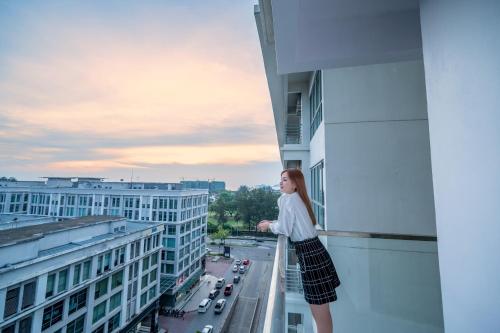 a girl standing on a balcony looking out at the city at Ritz Residence, Imago Mall Loft B in Kota Kinabalu