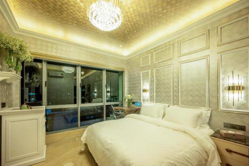 a bedroom with a large white bed and a chandelier at Ritz Residence, Imago Mall Loft B in Kota Kinabalu