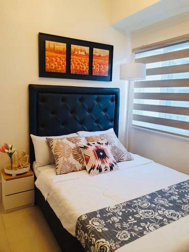 a bedroom with a bed with a blue headboard at 1 Br CONDO Vine Residences Quezon City with POOL NETFLIX WIFI VIDEOKE BOARD GAMES in Manila