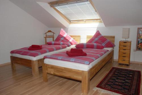 two beds with red pillows in a room at Klosterherberge Economy in Meßkirch