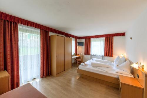 een hotelkamer met een groot bed en een bureau bij Hotel Gran Pre in San Vigilio Di Marebbe
