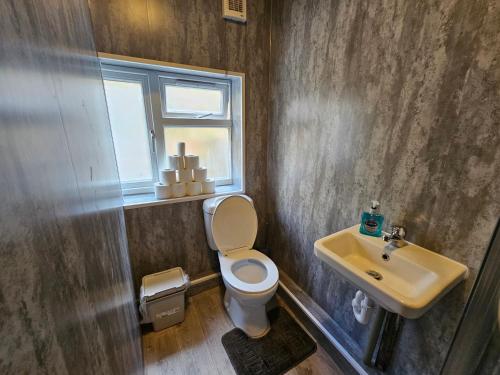 a bathroom with a toilet and a sink and a window at Family room near Queen Mary College in London