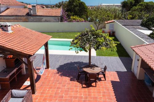 a patio with a table and a tree next to a pool at Retiro da Atafona Beach Pool House Yellow 