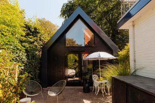 ein kleines Haus mit einem schwarzen Dach und einer Terrasse in der Unterkunft Studio Verver in Bergen