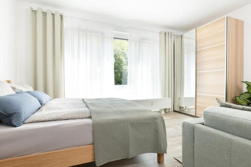 ein Schlafzimmer mit einem Bett, einem Sofa und einem Fenster in der Unterkunft Apart4me Scandi Apartment Geislingen zentral mit Parkplatz in Geislingen an der Steige