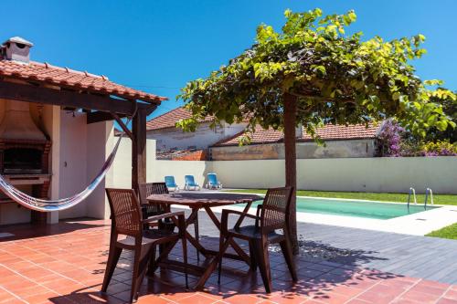 um pátio com uma mesa e cadeiras ao lado de uma piscina em Retiro da Atafona Beach Pool House Yellow 