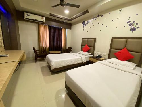 a hotel room with two beds with red pillows at Hotel Rituraj in Guwahati