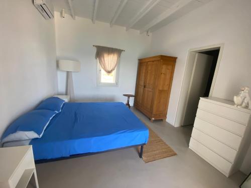 - une chambre avec un lit bleu, une commode et une fenêtre dans l'établissement Villa Baldin, à Lipsi