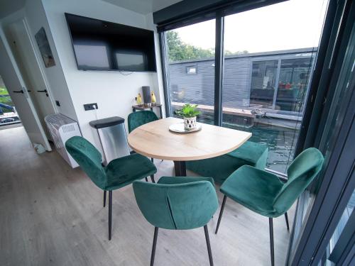 een tafel en groene stoelen in een kamer met een raam bij Houseboats Mookerplas met dakterras in Middelaar