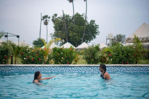 duas mulheres estão a nadar numa piscina em Unity Holiday Resort - Statue Of Unity em Kevadia