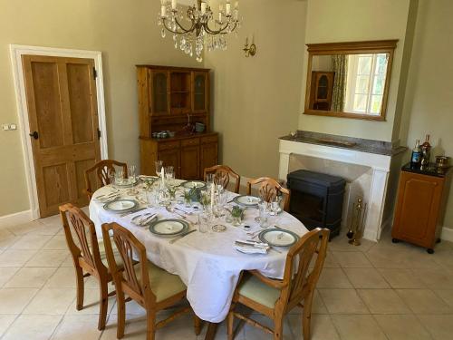 uma sala de jantar com uma mesa com cadeiras e um lustre em Le Manoir aux Volets Verts em Salerm