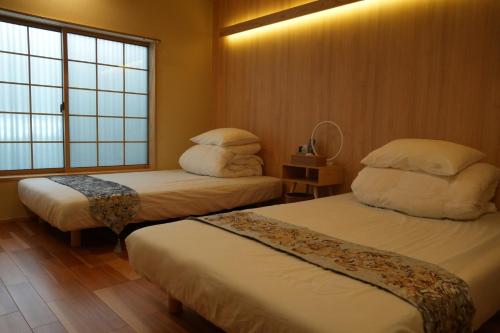 a hotel room with two beds and a window at Kyoto-cocoro house in Kyoto
