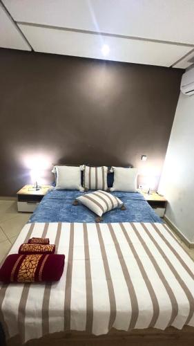 a large bed with two pillows on it in a room at Tanagra Mall appartement de Luxe a côté de la Gare TGV in Kenitra