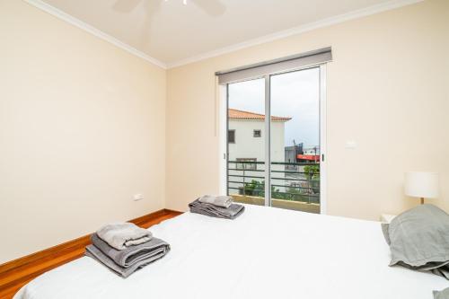 a white bedroom with two beds and a large window at Bela Vista Valley in Calheta