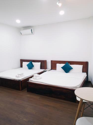 two twin beds in a room with a table and chairs at Hero Hostel & Billiards in Chau Doc