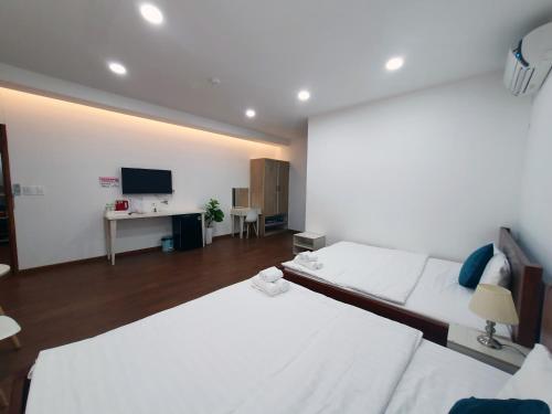 a bedroom with two white beds and a television at Hero Hostel & Billiards in Chau Doc