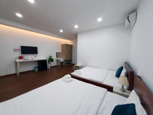 a hotel room with two beds and a television at Hero Hostel & Billiards in Chau Doc