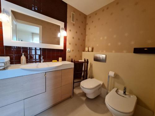 ein Badezimmer mit einem Waschbecken, einem WC und einem Spiegel in der Unterkunft Apartamento Los Cármenes in Playa de Gandia
