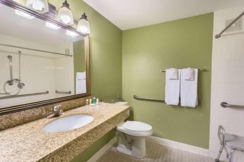 a bathroom with a sink and a toilet and a mirror at Days Hotel by Wyndham Mesa Near Phoenix in Mesa