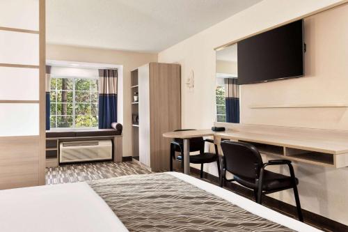 a hotel room with a bed and a desk and chairs at Microtel Inn & Suites by Wyndham Florence/Cincinnati Airpo in Florence